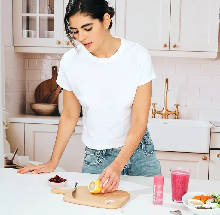 Woman in a kitchen preparing food on a cutting board.