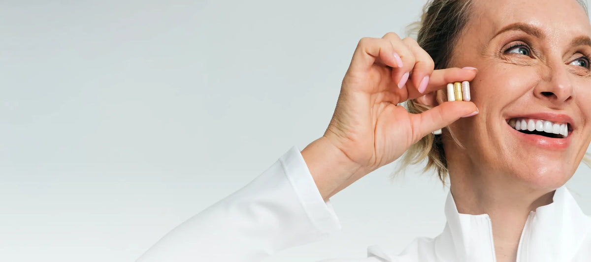 Smiling woman holding a probiotic capsule near her mouth