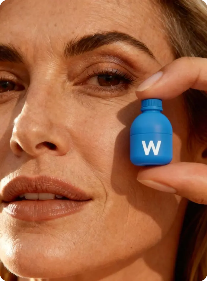 Close-up of a person holding a blue container with a 'W' logo near their face.