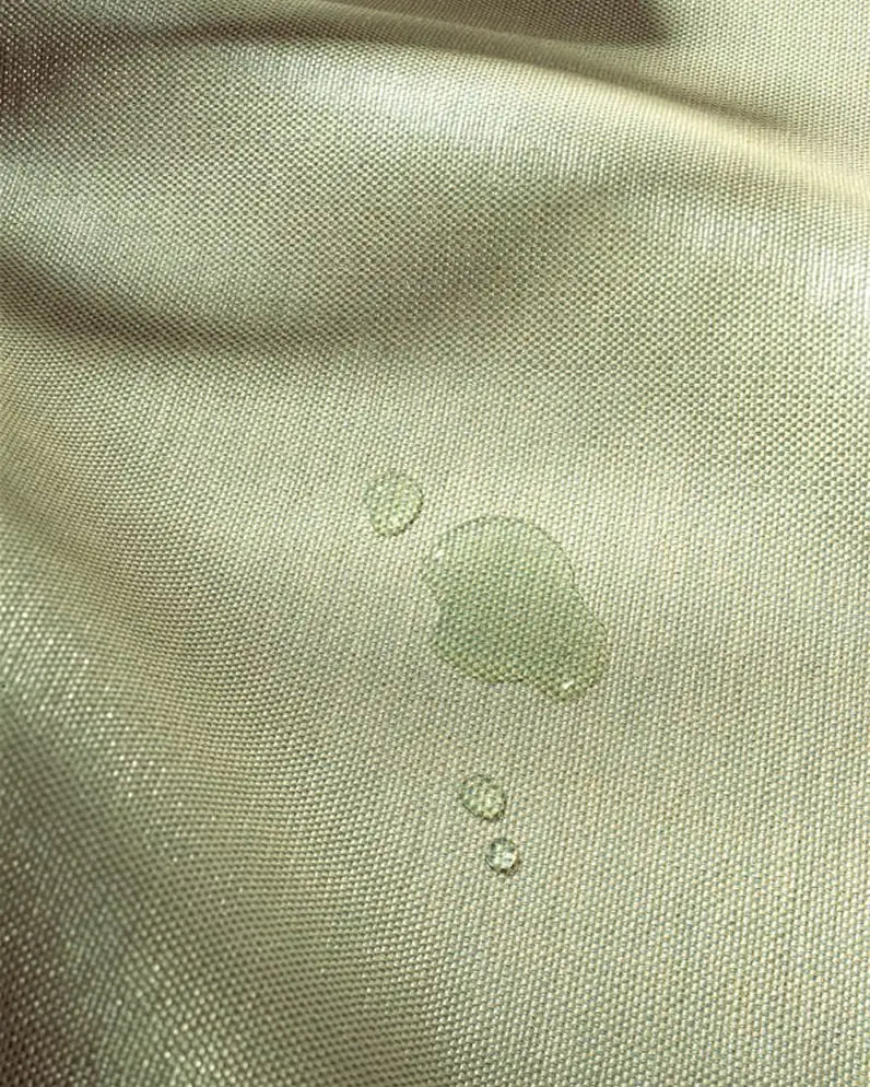 Close-up of green fabric with water droplets on a textured surface